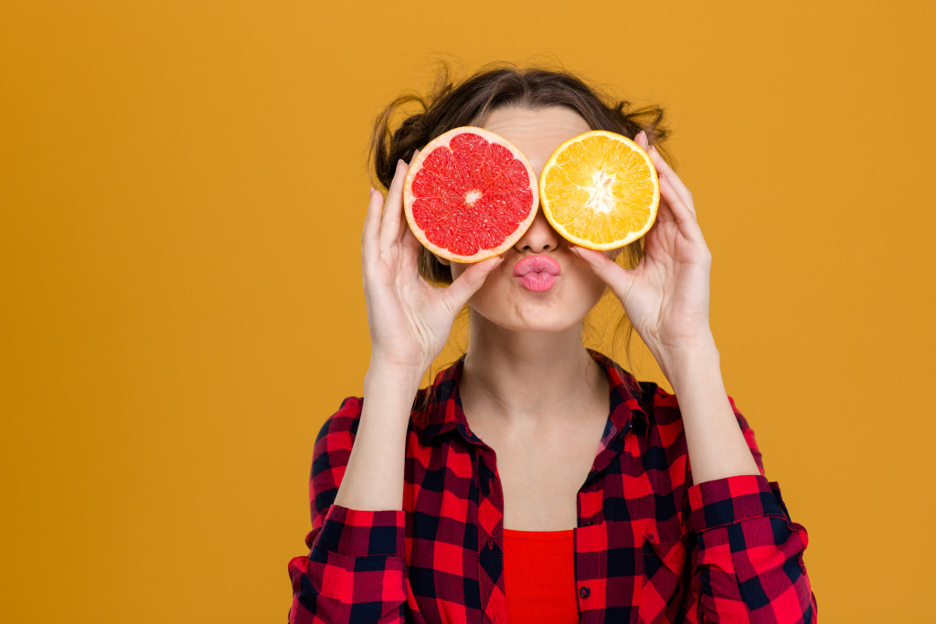 woman with citrus fruits covering her eyes
