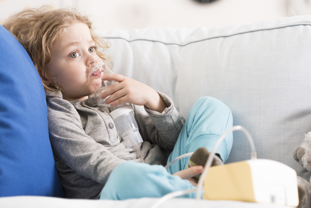child using nebulizer sitting on the sofa