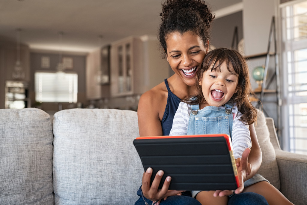 a mother and her child happily watching on a tablet